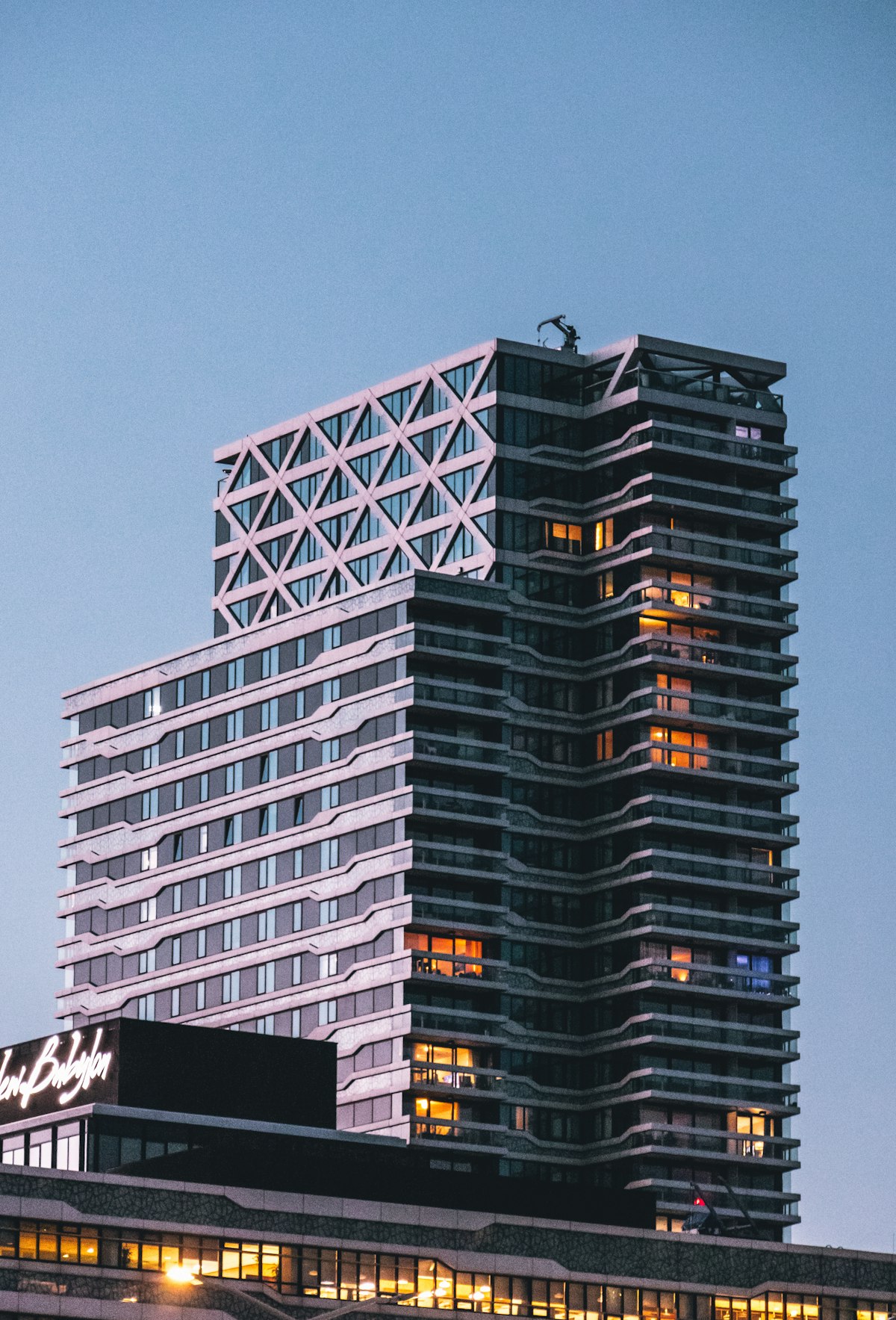 A modern high-rise tower lit against the twilight sky.